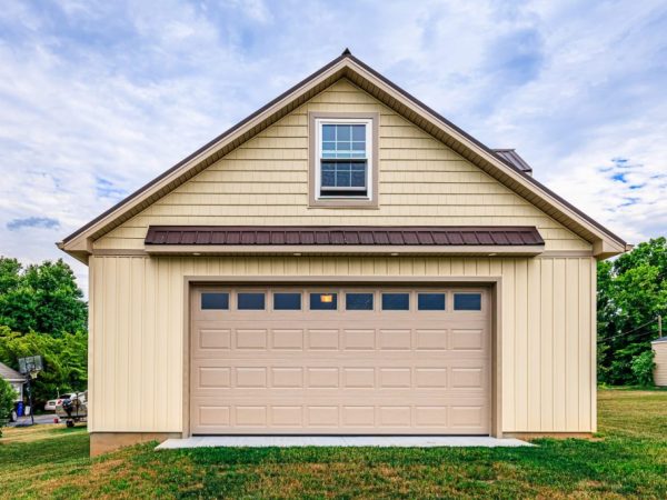 Front view of a beige detached garage with a brown metal roof and one garage door.