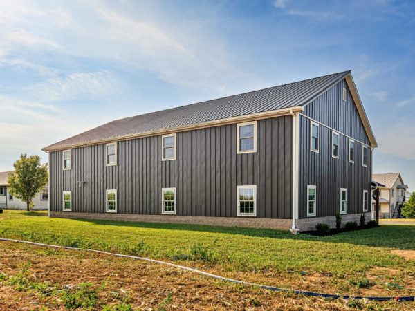Large two-story commercial garage with dark vertical siding and white trim.