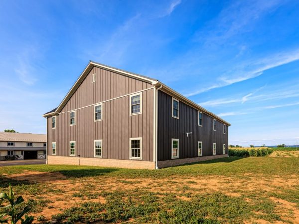Side view of a long garage building with metal siding and multiple evenly spaced windows.
