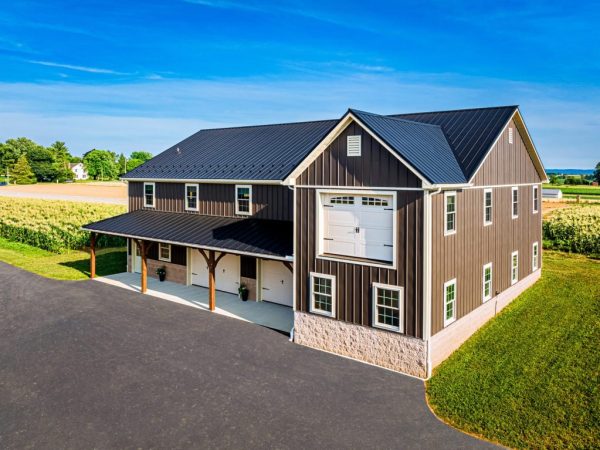 Aerial angle of a metal commercial garage with black roof, white garage doors, and wide driveway.