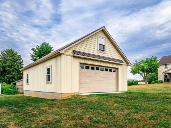 Side view of a beige detached garage with a single garage door and two windows.