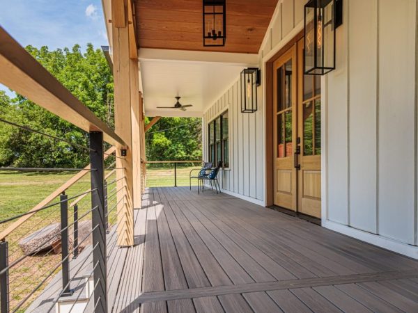 Close-up of the porch with gray composite decking, black railing, and wood ceiling.