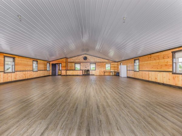 Large finished room with wood paneling, vinyl plank flooring, and a white metal ceiling.