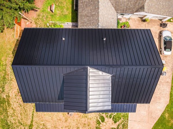 Angled roofline view showing black metal roof and upper dormer on a new house.