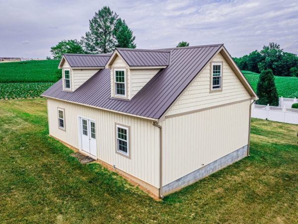 Back and side view of a cream-colored garage with brown metal roofing and twin dormers