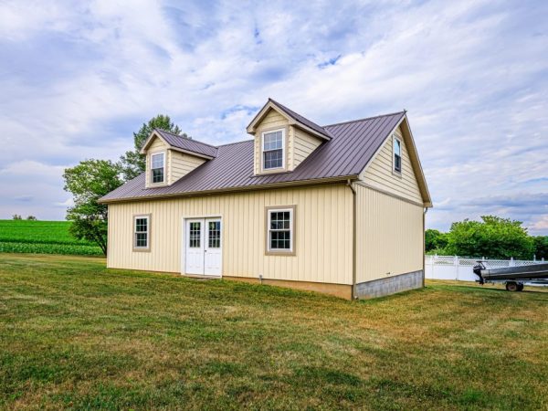 Angled rear view of a detached garage with cream siding and a brown metal roof