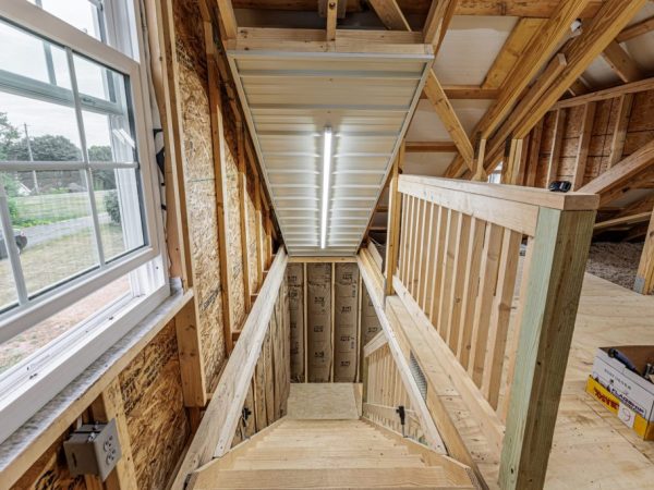 Wood-framed staircase inside an unfinished garage leading to the upper floor