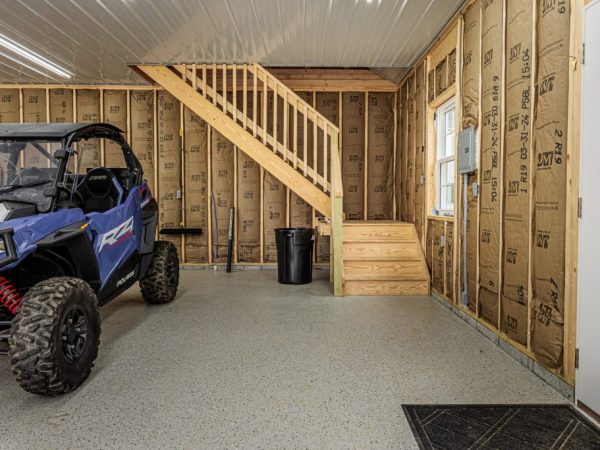 Polaris RZR parked inside a garage with unfinished walls and a wooden staircase