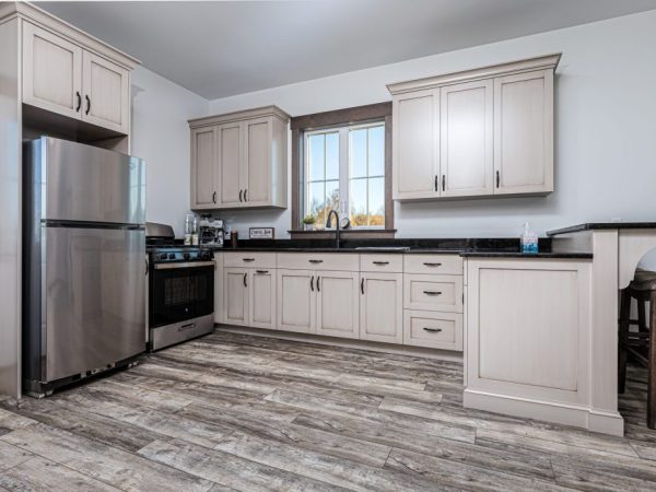 Kitchen with stainless steel appliances, light wood cabinets, and bar seating, in a custom garage apartment.