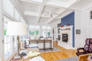 elegant 4 season room with coffered ceiling, hardwood floors, and fireplace, connected to an outdoor deck via French doors
