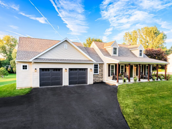 angled view of home with attached garage and front porch, surrounded by trees and lawn