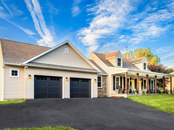 angled view of home with attached garage and front porch, surrounded by trees and lawn
