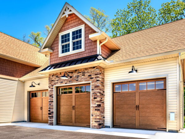 straight on view of three garage doors beneath a dormer window with decorative trim and black awning