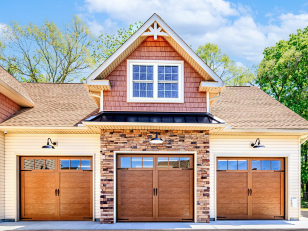 front view of three wood look garage doors with stone facade and decorative gable trim