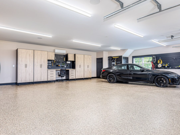 spacious garage interior with epoxy floor, black car, and wall-mounted tool cabinets