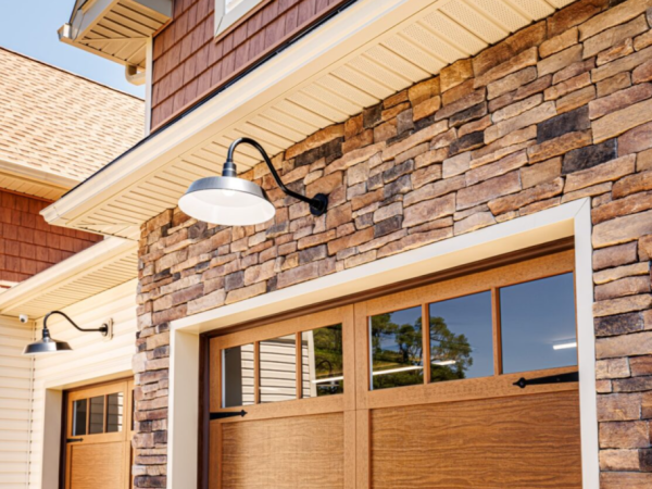 close up of stone exterior wall above garage doors with black gooseneck lighting